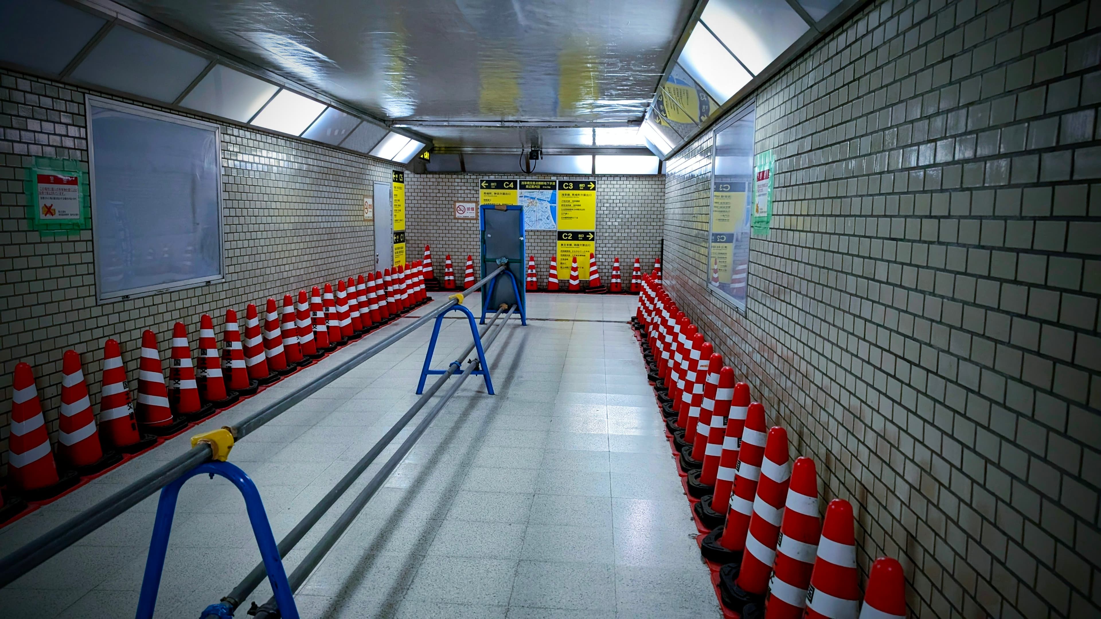 日本の地下通路の写真。通路の中央には柵、壁際には大量のカラーコーンが設置されている
