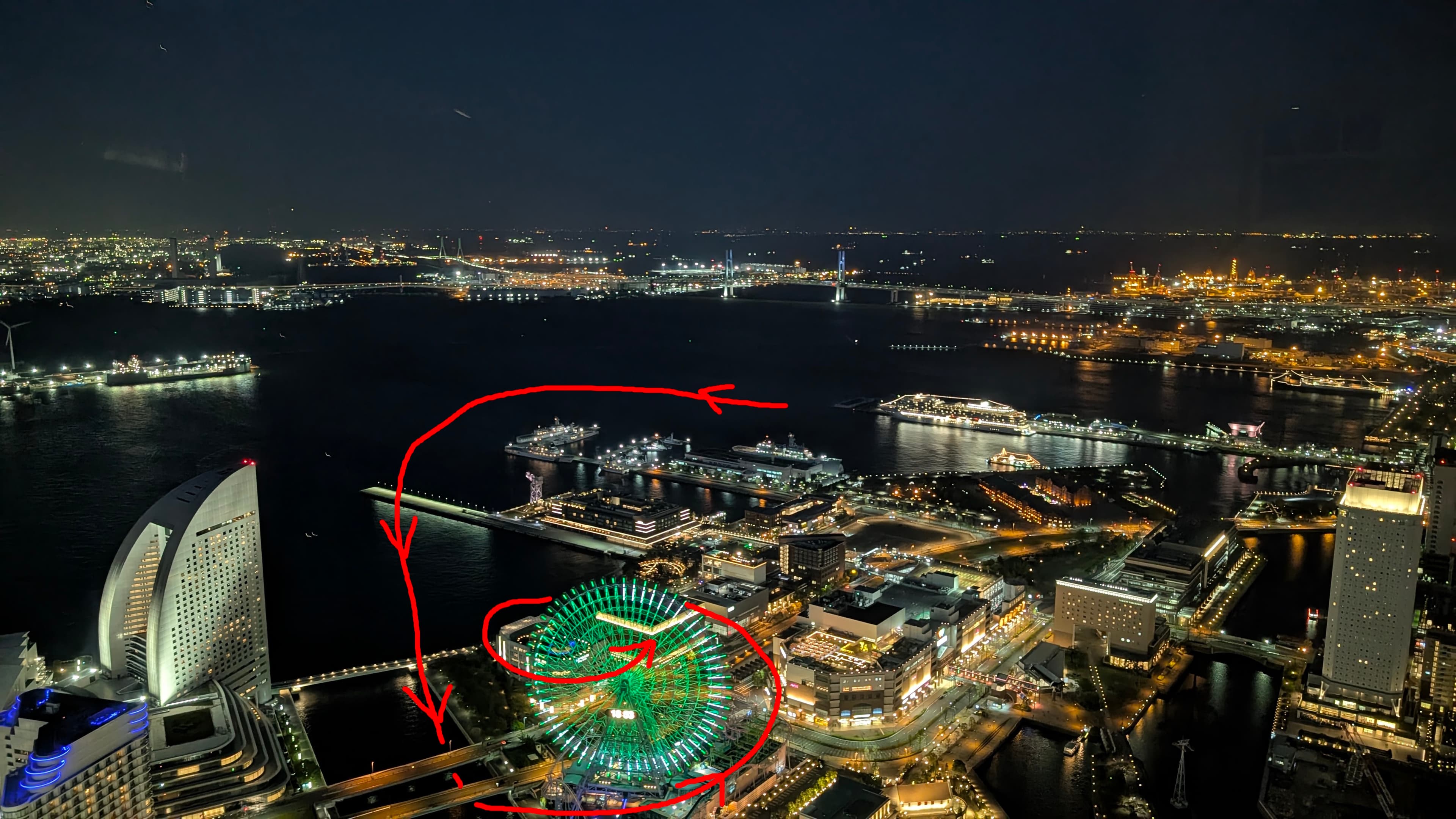 横浜の夜景の写真。観覧車が写っており、赤い矢印でカメラワークが示されている